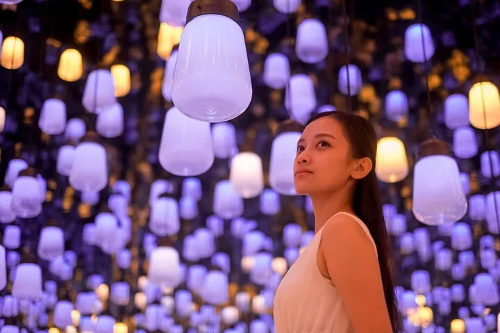 A visitor standing among glowing hanging lanterns inside teamLab Borderless at Azabudai Hills, Tokyo